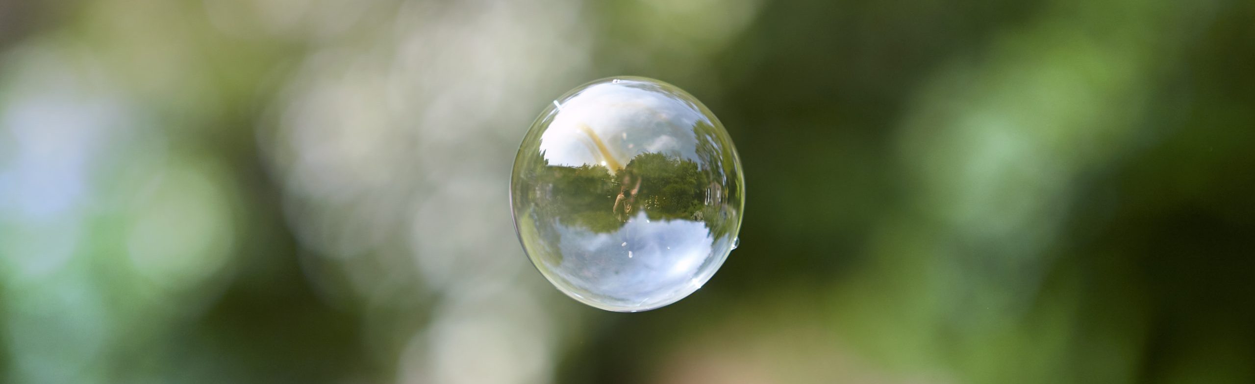 Bulle flottant dans l'air devant un fond de nature flou. Apaisement, calme.