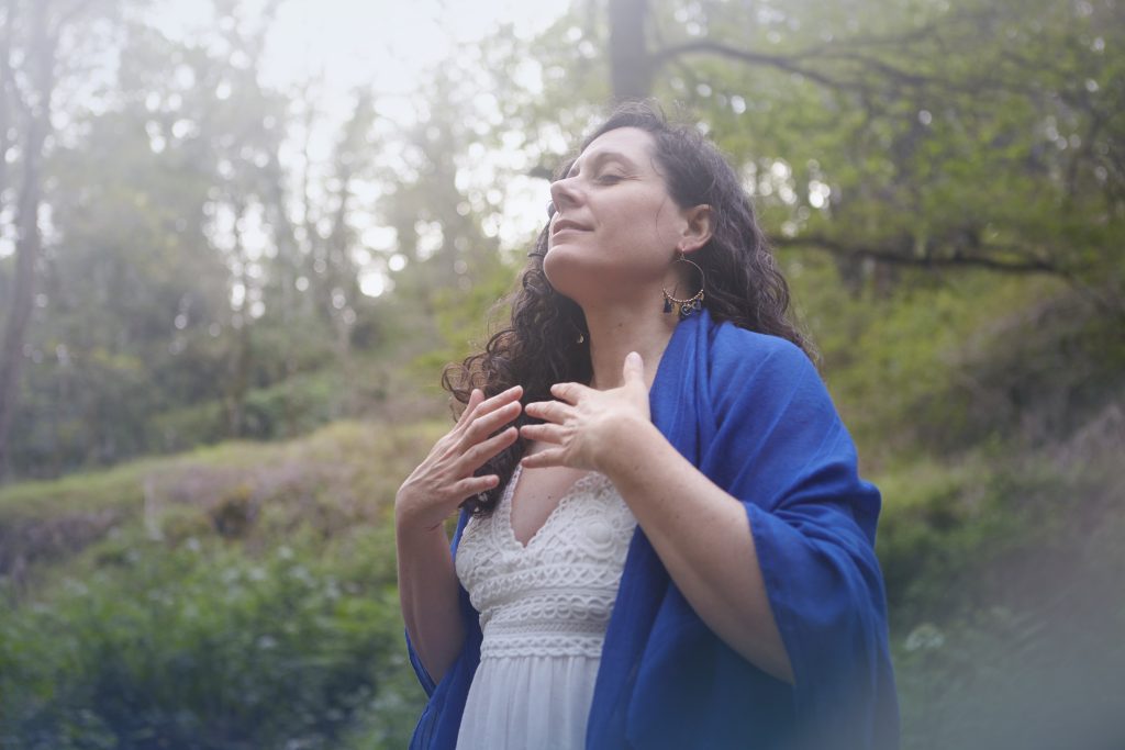 Femme en grande connexion avec elle même et la nature, dans la forêt. Les mains sur le cœur, pleine de sérénité et d'amour de la vie.