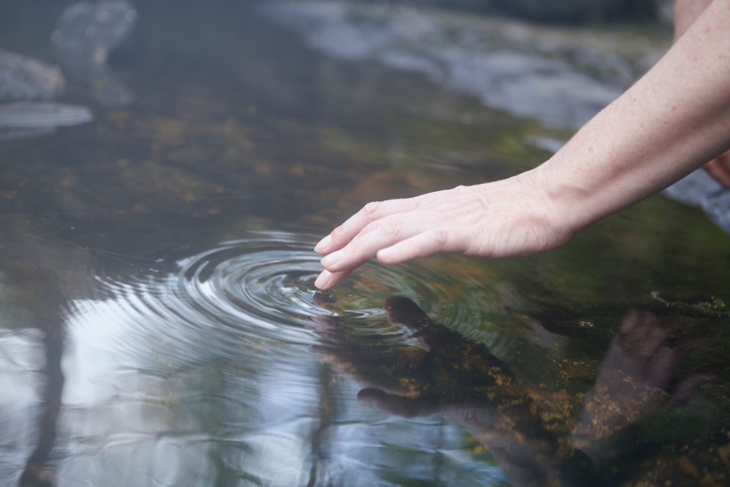 Main qui touche l'eau et créer une onde en cercle. Sérénité et confiance.